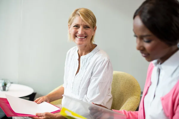 Femme souriant à la caméra pendant que son collègue lisait le document — Photo