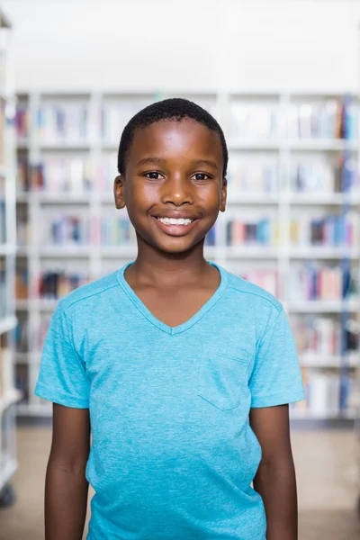 Lycklig skolpojke står i biblioteket — Stockfoto