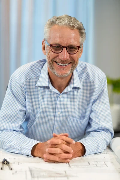 Portret van lachende zakenman met blauwdruk op Bureau — Stockfoto