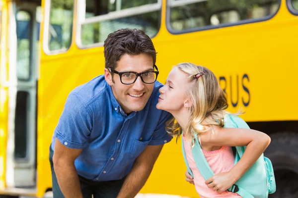 Écolière sur le point d'embrasser un professeur devant le bus scolaire — Photo