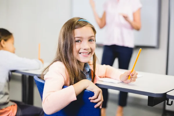 Portræt af skolepige smilende i klasseværelset - Stock-foto