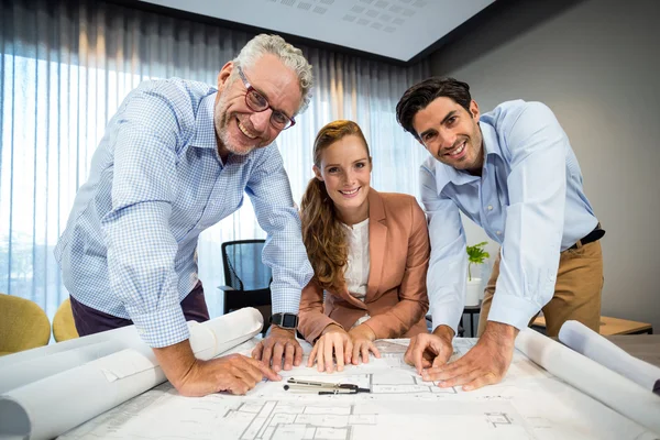 Geschäftsfrau und Mitarbeiterin mit Blaupause auf dem Schreibtisch — Stockfoto