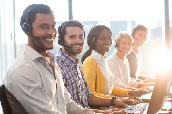 Team van collega's die werken op hun bureau met headset — Stockfoto