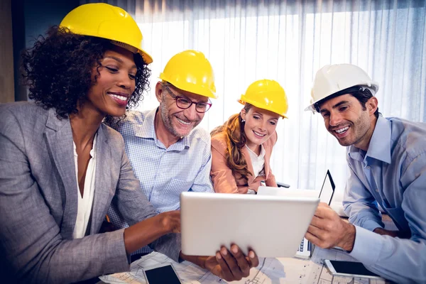 Arquitectos sonrientes discutiendo sobre tableta digital en la oficina —  Fotos de Stock