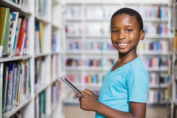 Schoolboy usando tablet digital na biblioteca — Fotografia de Stock