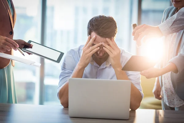 Affärsman som sitter på skrivbord med handen på huvudet — Stockfoto