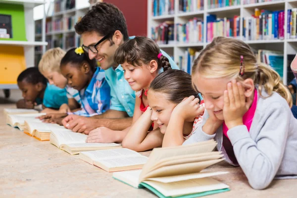 Enseignant et enfants lisant un livre à la bibliothèque — Photo