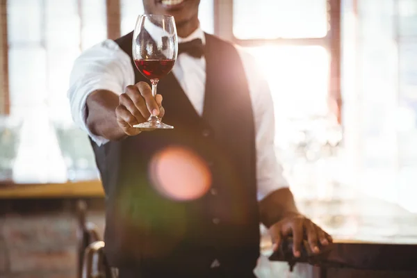 Mid section of bartender offering a glass of wine — Stock Photo, Image