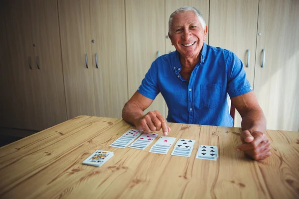 Portrait of smiling senior man pointing at a card — Stock Photo, Image