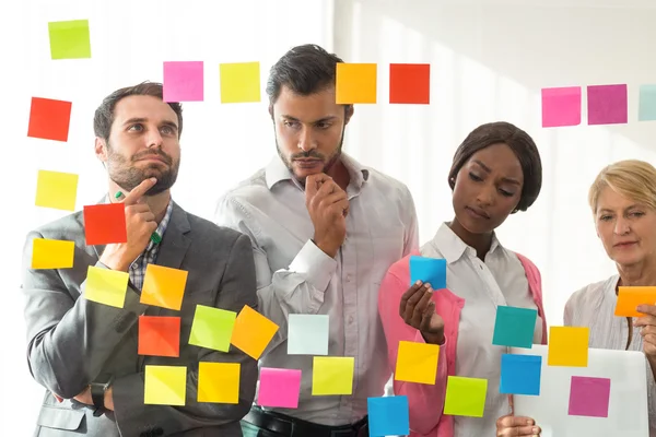 Gente de negocios mirando notas adhesivas — Foto de Stock