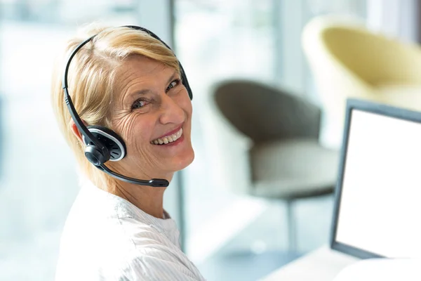 Vrouw die werkt op computer met headset — Stockfoto