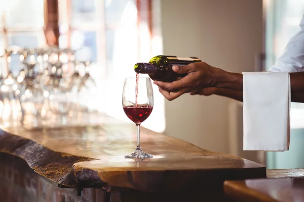 Barman derramando vinho tinto em um copo — Fotografia de Stock