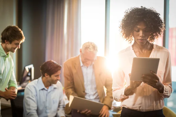 Affärskvinna som arbetar med digital tablet med medarbetare i backgro — Stockfoto