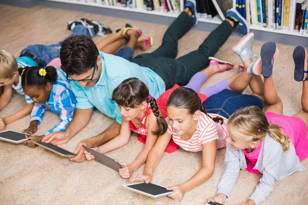 Professor e crianças usando tablet digital na biblioteca — Fotografia de Stock