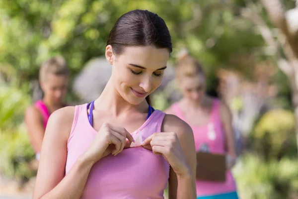 Female volunteer putting ribbon on her vest — Stock Photo, Image