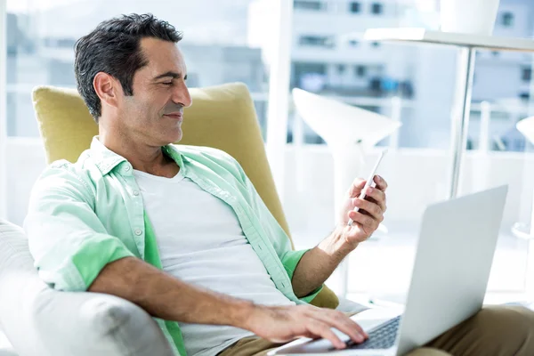 Homem usando celular no sofá — Fotografia de Stock