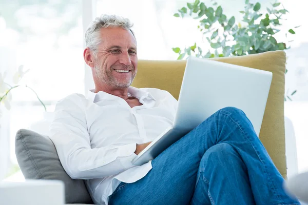 Lachende volwassen man met laptop — Stockfoto