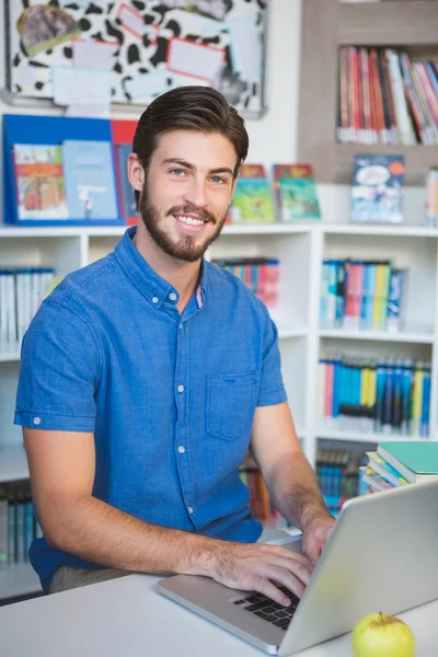 School teacher working on laptop in library — Stock Photo, Image