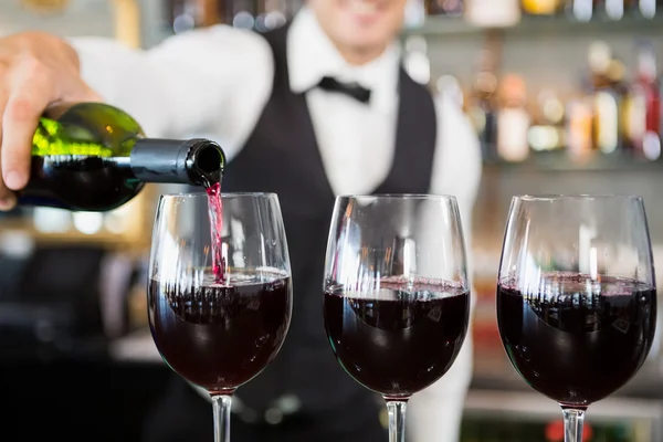 Waiter pouring wine into glasses — Stock Photo, Image