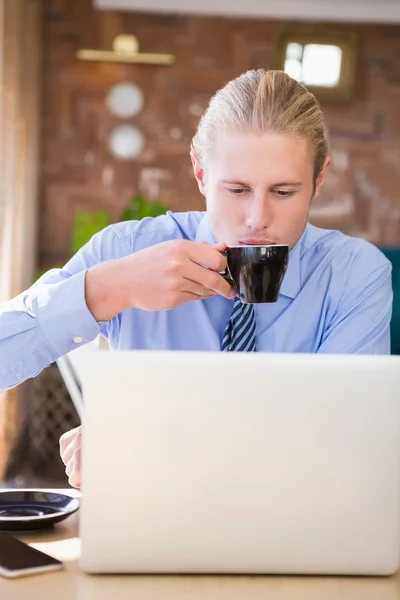 Homme prenant un café tout en utilisant un ordinateur portable — Photo