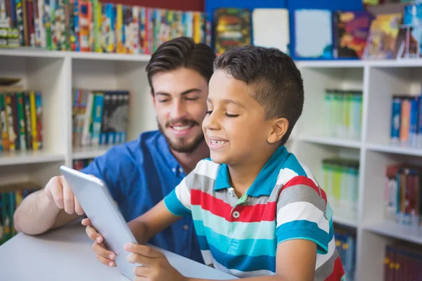 Leraar en school kind met behulp van digitale tabel in bibliotheek — Stockfoto