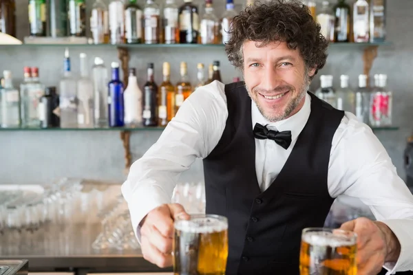 Waiter serving mug of beers — Stock Photo, Image