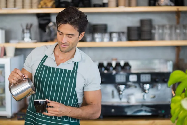 Garçom sorrindo derramando uma xícara de café — Fotografia de Stock