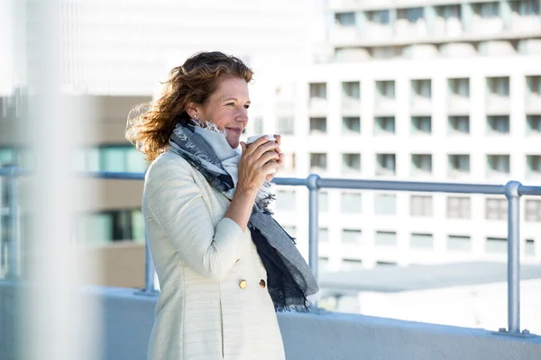 Woman drinking coffee by railing — Stock Photo, Image