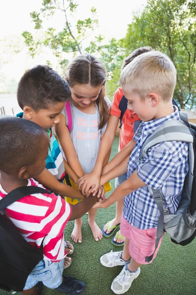 Schoolkids putting their hands together in campus — Stock Photo, Image