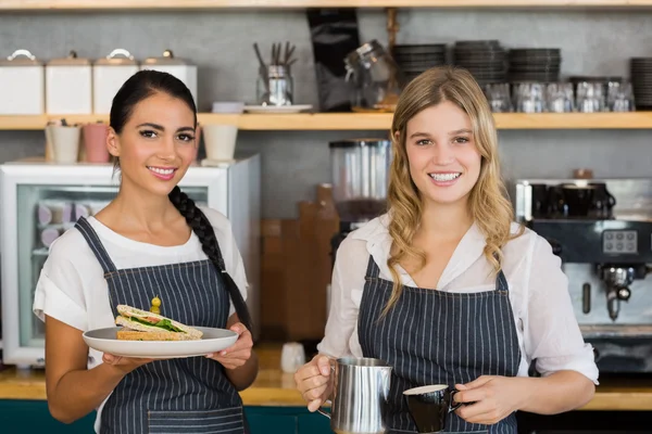 Twee serveersters holding plaat van maaltijd en koffie kruik — Stockfoto