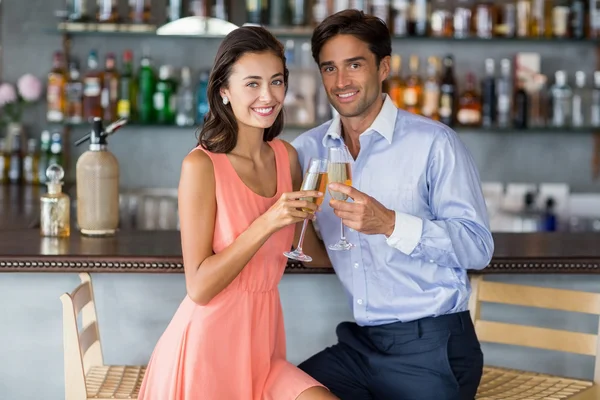 Casal sentado no balcão do bar e brindar a um óculos — Fotografia de Stock