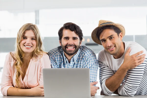 Retrato de mujer sonriente y dos hombres usando laptop — Foto de Stock