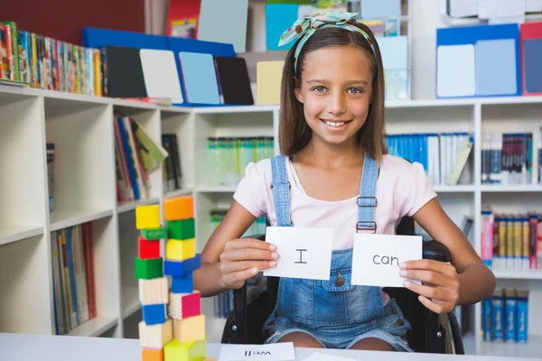 Девушка-инвалид показывает плакат с надписью "Я могу в библиотеке" — стоковое фото