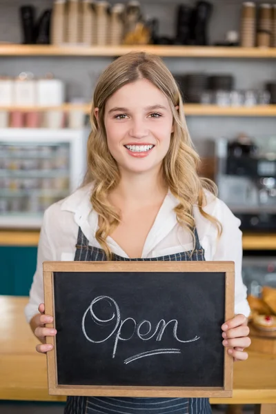 Glimlachend serveerster weergegeven: schoolbord met open teken bij café — Stockfoto