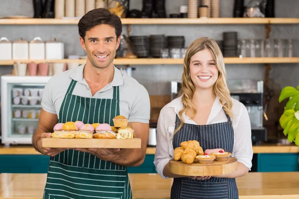 Kellnerin und Kellnerin mit einem Tablett mit Cupcakes — Stockfoto