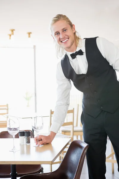 Waiter standing at table with empty glass — Stock Photo, Image