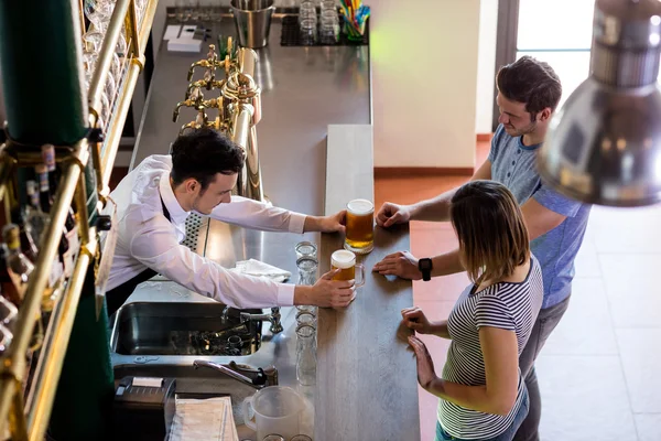 Barman servindo cerveja para casal — Fotografia de Stock