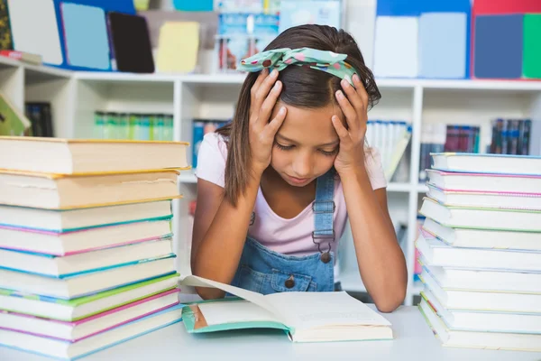 School meisje het lezen van een boek in de bibliotheek — Stockfoto