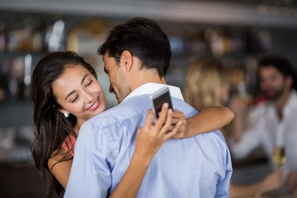 Жінка перевіряє мобільний телефон, приймаючи чоловіка — стокове фото