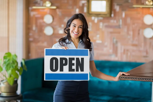 Lachende serveerster houden een bord met open teken in restaurant — Stockfoto