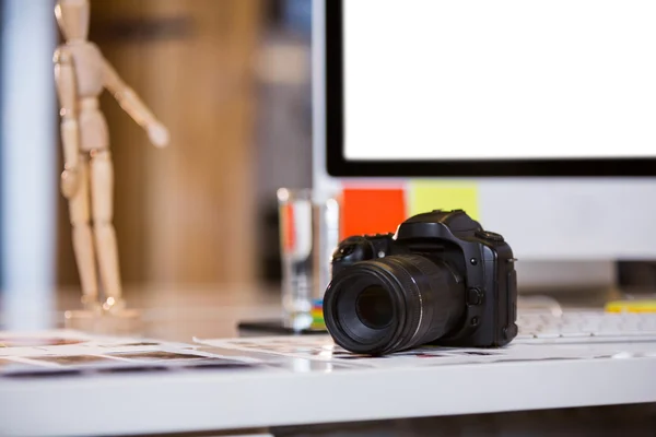 Camera on photographs at computer desk — Stock Photo, Image