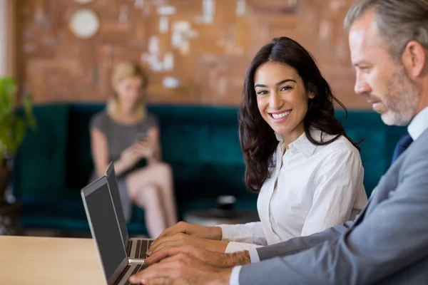 Compañeros de negocios sentados en la mesa y usando laptop — Foto de Stock