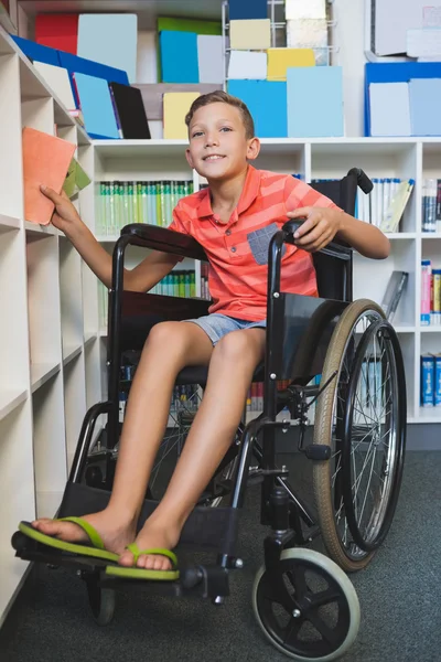 Disabled schoolboy selecting a book — Stock Photo, Image