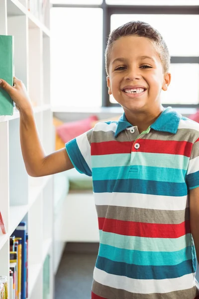 Boy taking a book from bookshelf in library — Stock Photo, Image