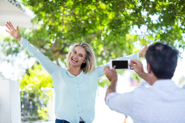 Man fotograferar glad kvinna mot träd — Stockfoto