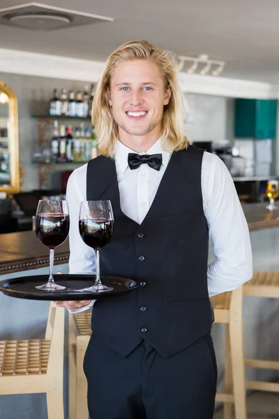 Retrato del camarero sosteniendo bandeja con copas de vino tinto —  Fotos de Stock