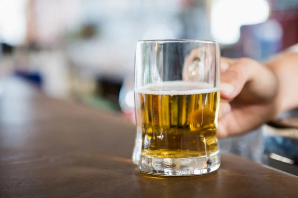 Close-up de homem segurando caneca de cerveja no balcão — Fotografia de Stock