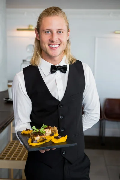 Waiter holding a plate of food in restaurant — Stock Photo, Image