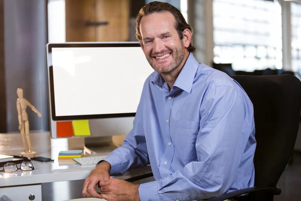 Businessman sitting by computer desk — Stock Photo, Image