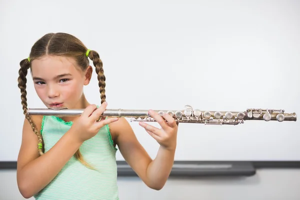 Porträtt av leende skolflicka spelar flöjt i klassrummet — Stockfoto